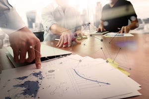 business documents on office table with smart phone and laptop computer and graph financial with social network diagram and two colleagues discussing data in the background-1